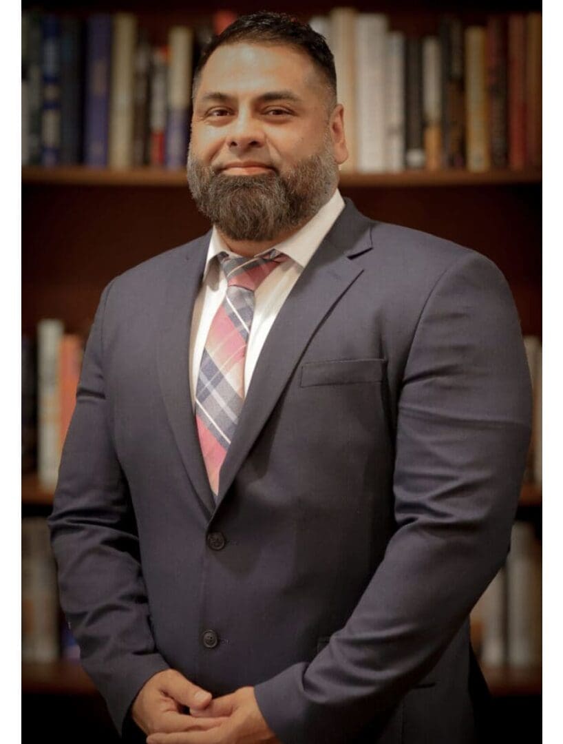Man in suit standing before bookshelf.